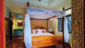 Una cama con dosel, cabecera de madera y varias almohadas.