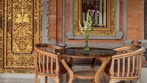 Una habitación tradicional con una mesa y sillas de madera, un jarrón con flores, y puertas y ventanas de oro ornamentado.