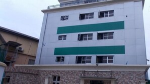 A multi-story building with a white facade and green horizontal stripes. - Divine Foutain Apapa Branch (Lagos)