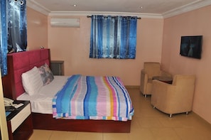 A bedroom with a bed, a desk, a chair, and a TV. - Divine Foutain Apapa Branch (Lagos)