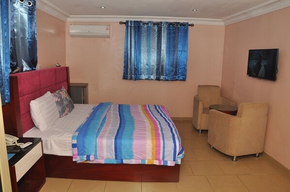 A bedroom with a bed, a desk, a chair, and a TV. - Divine Foutain Apapa Branch (Lagos)