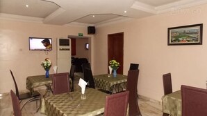 A dining area with tables covered in checkered tablecloths, chairs, and vases with flowers. - Divine Foutain Apapa Branch (Lagos)