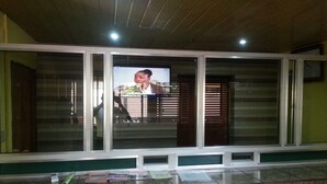 A reception area with a marble counter, a television screen displaying a person, and a wooden ceiling. - Divine Fountain Agidingbi (Lagos)