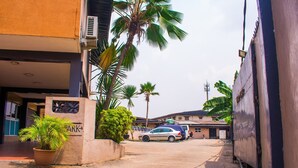 A narrow street with a parked car, a potted plant, and a building with a sign that reads "ARK". - Divine Fountain Agidingbi (Lagos)