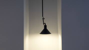 A pendant light fixture hanging from the ceiling in a room with plain walls.