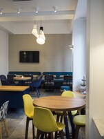 Un comedor moderno con mesas redondas, sillas coloridas e iluminación colgante.
