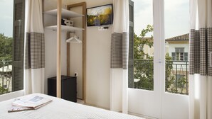 Une chambre d’hôtel avec un lit, un téléviseur fixé au mur et un balcon donnant sur l’extérieur.