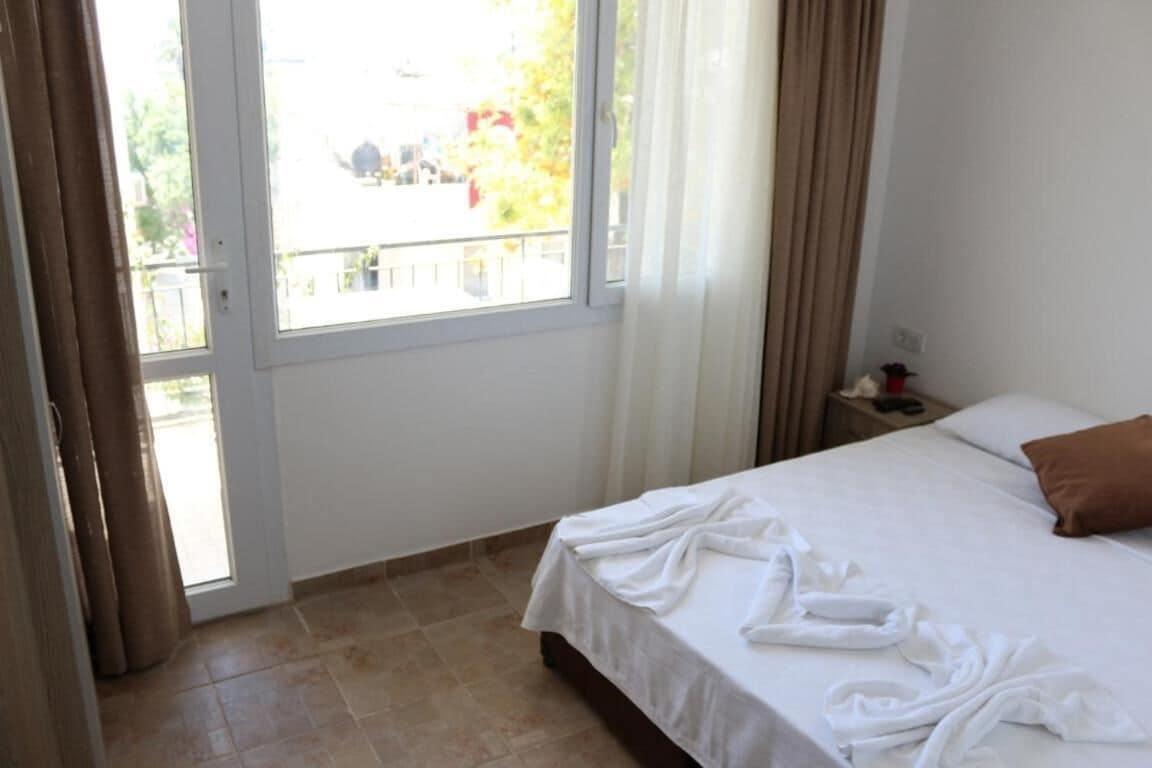 Een hotelkamer met een bed, een raam en een nachtkastje.