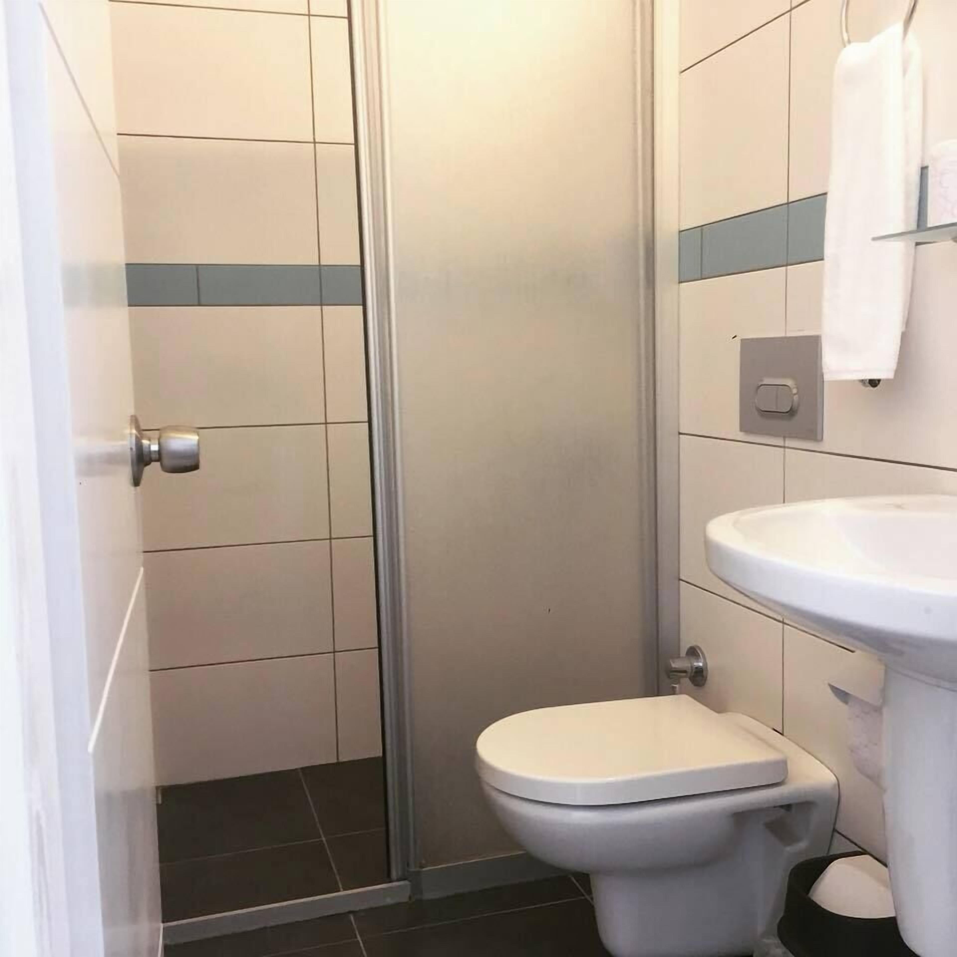 A bathroom with a toilet, a sink, and a shower area.