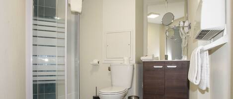 Une salle de bain avec une douche à parois de verre, des toilettes, un meuble-lavabo avec un miroir et un porte-serviettes.