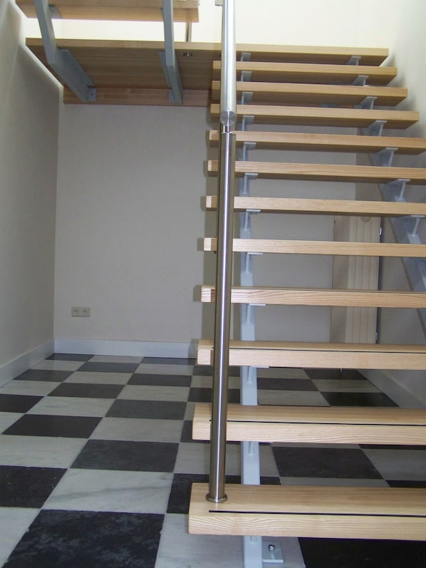 A staircase with wooden steps and metal railings in a room with a checkered floor. - Hotel Het Oude Postkantoor (Brummen)