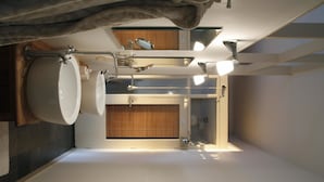 A modern bathroom with a large sink, mirror, and ceiling fan. - Hotel Het Oude Postkantoor (Brummen)