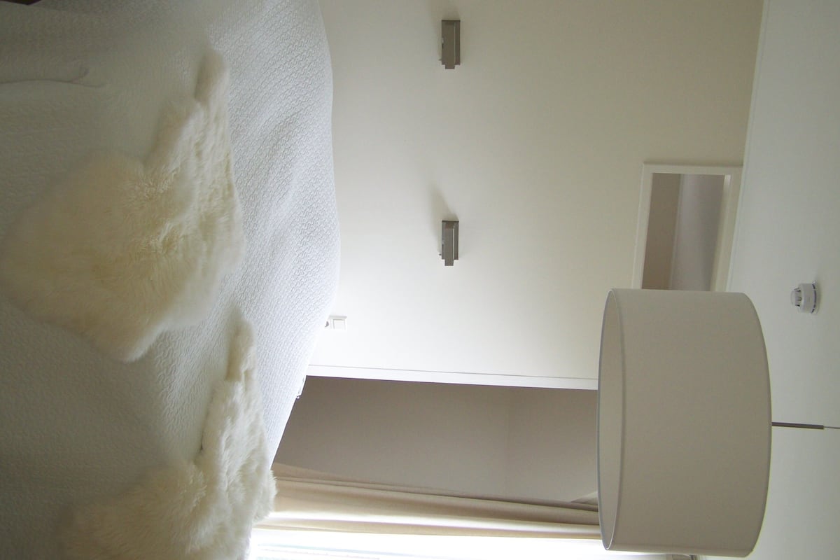 A room with a white ceiling, a light fixture, and a window with blinds.
