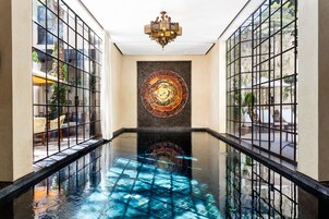 Un vestíbulo de hotel con un estanque reflectante, una gran pared decorativa y un candelabro.