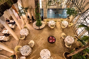 An indoor dining area with round tables, chairs, and potted plants.