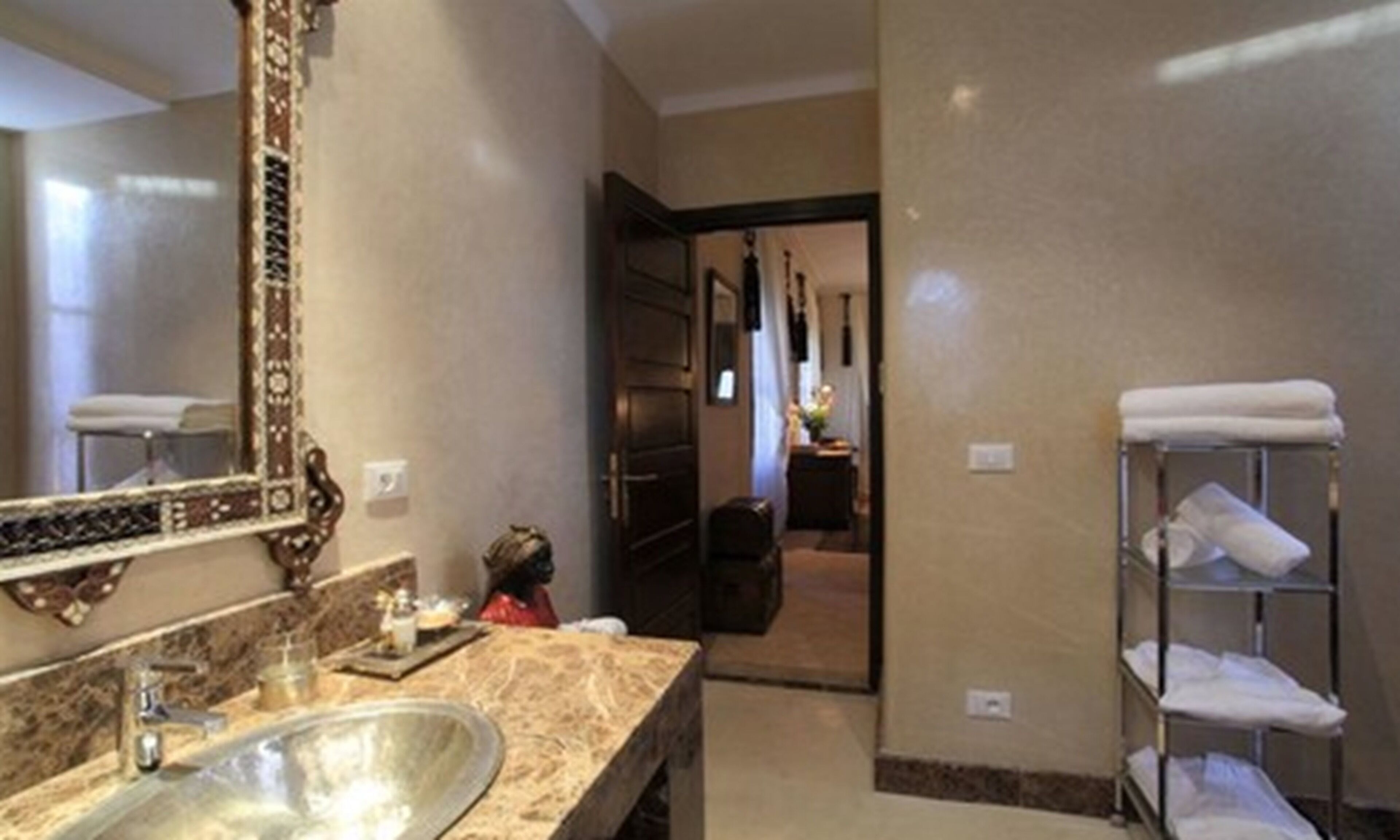 Un baño de hotel con un lavabo de mármol, un espejo grande y un perchero para toallas.