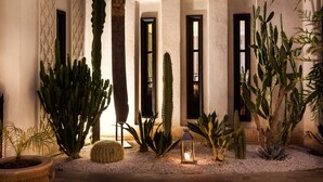 A courtyard with cacti and a lantern, featuring a textured wall and a doorway with a window. - Palais Khum (Marrakech)