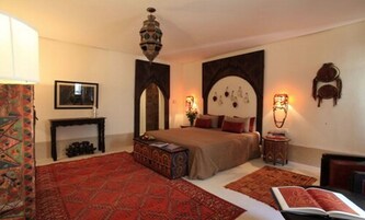 Un dormitorio con cama, mesita de noche, cómoda, espejo y candelabro.