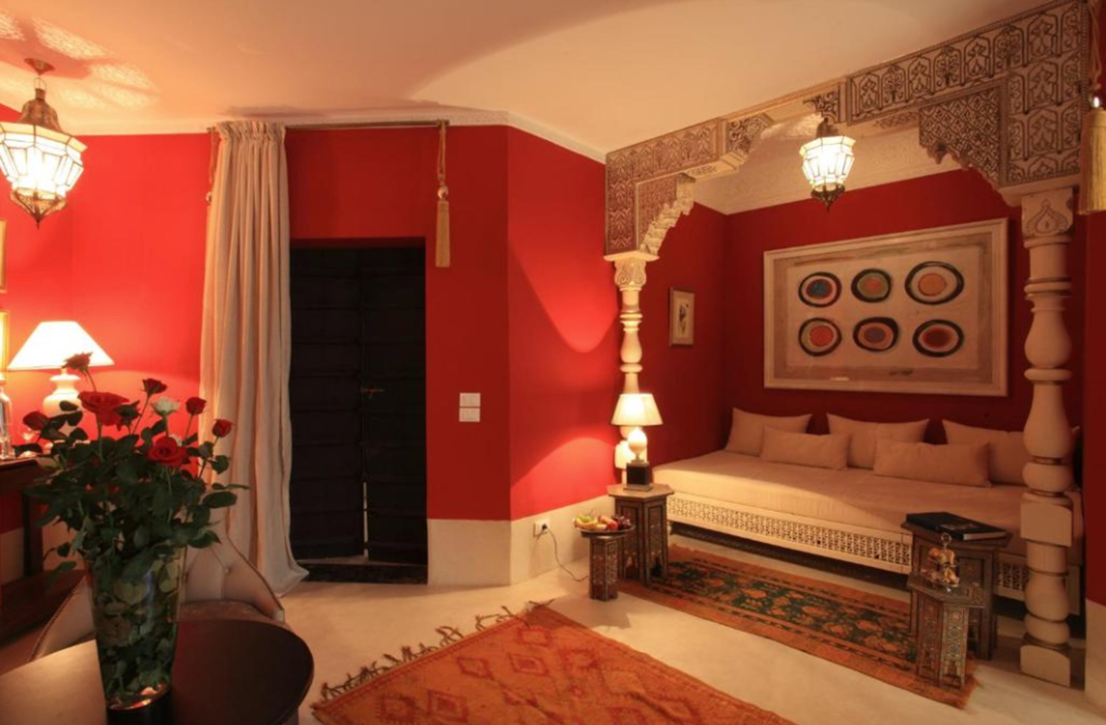 A room with a bed, a lamp, a vase with flowers, and a patterned rug.
