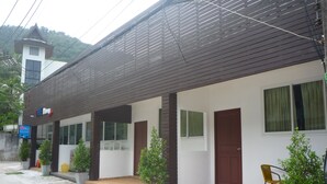 Un edificio de dos pisos con revestimiento de madera y fachada blanca. Se observan dos puertas, una en la planta baja y otra en el piso superior.
