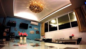 Una sala de estar moderna con un amplio ventanal, un televisor de pantalla plana y una lámpara decorativa en el techo.