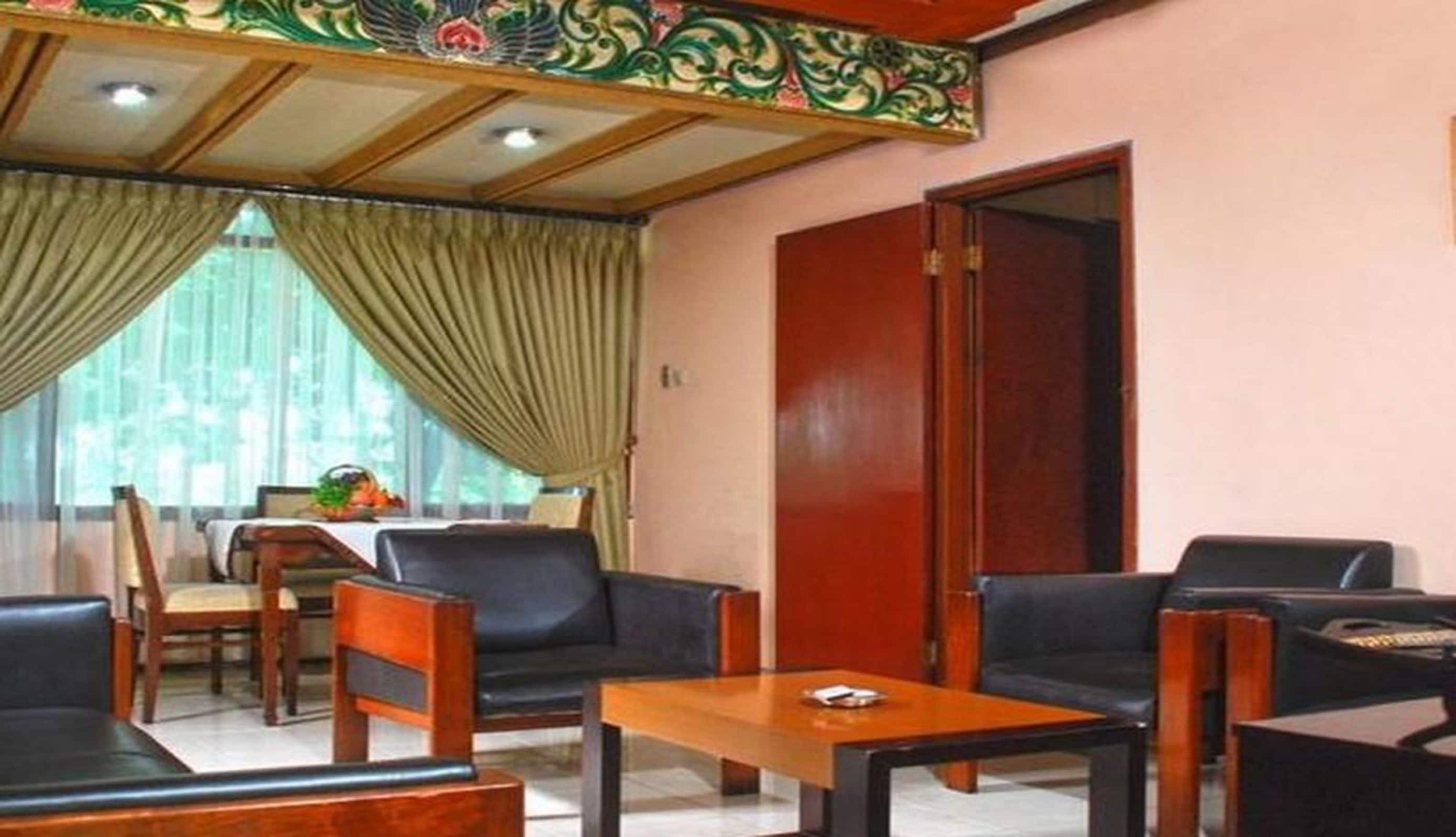 A hotel room with a dining area, wooden furniture, and a decorative ceiling.
