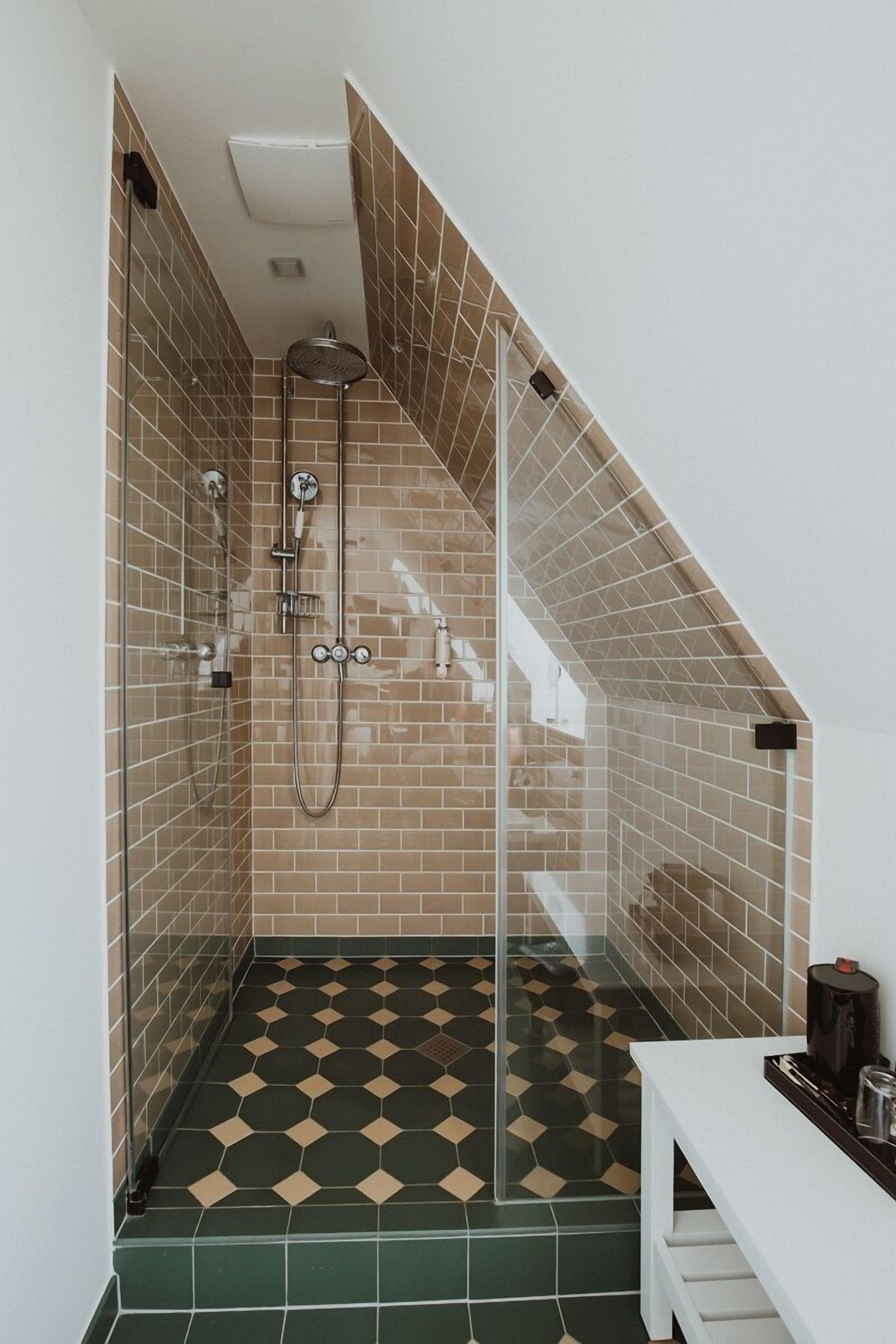 Un baño moderno con cabina de ducha de vidrio, un banco y suelo de baldosas.