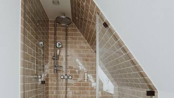 Un baño moderno con cabina de ducha de vidrio, un banco y suelo de baldosas.