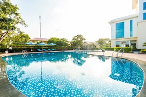 Una piscina al aire libre, sillones reclinables de piscina