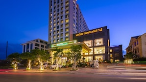A modern hotel with a prominent sign, a well-lit entrance, and a parking area. - Muong Thanh Luxury Nhat Le Hotel (Dong Hoi)