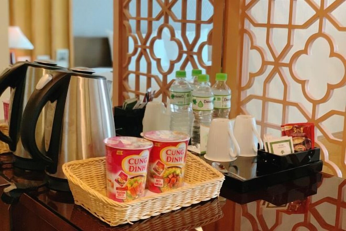 A kitchen counter with a kettle, a basket of Cung Dinh ice cream, bottled water, and a coffee maker.