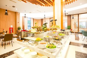 A buffet with various dishes and a seating area with chairs and tables. - Muong Thanh Luxury Nhat Le Hotel (Dong Hoi)