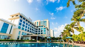 A hotel with a swimming pool, outdoor seating, and a clear blue sky. - Muong Thanh Luxury Nhat Le Hotel (Dong Hoi)