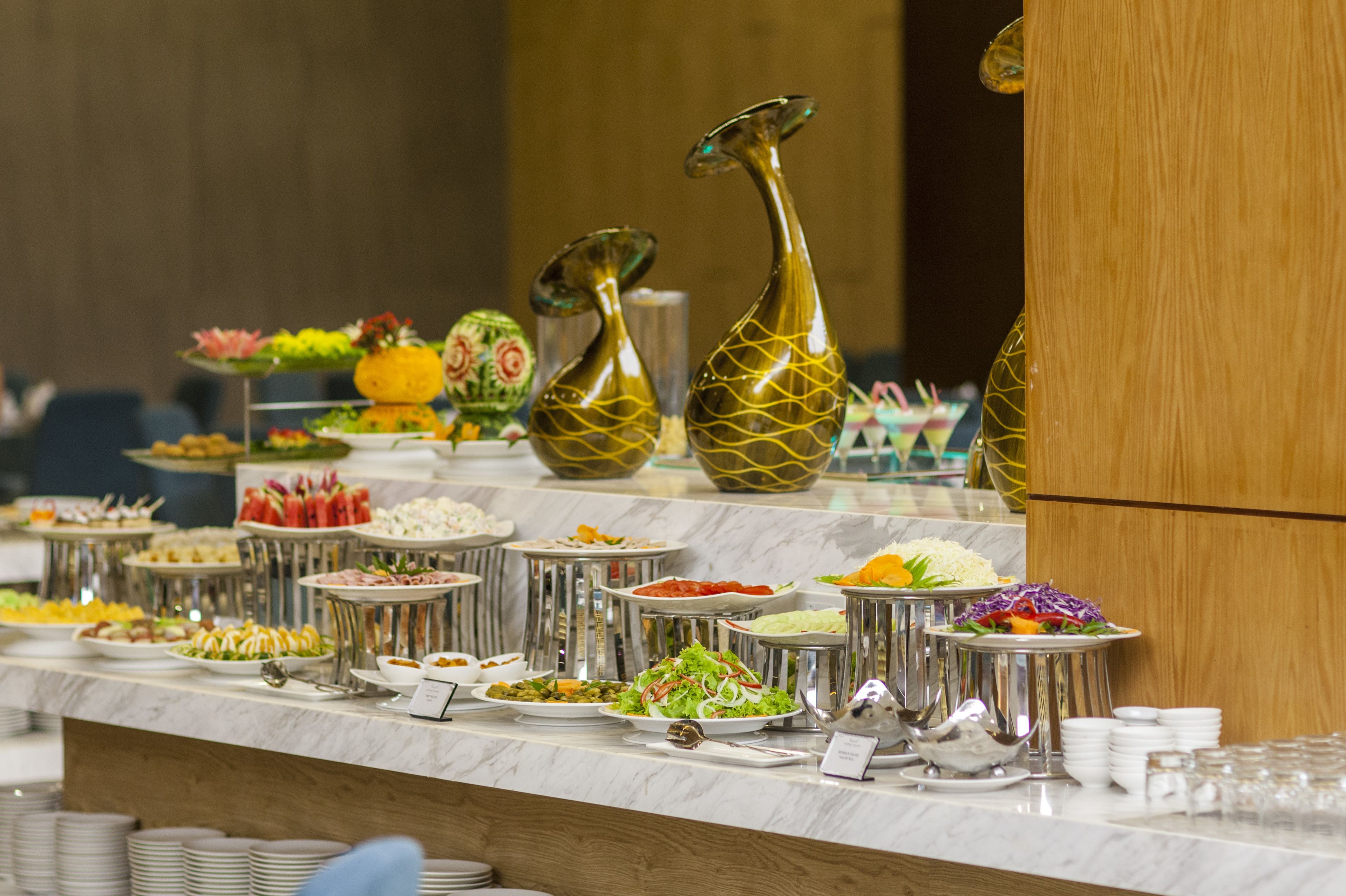 Un bufé con diferentes platillos y jarrones decorativos.