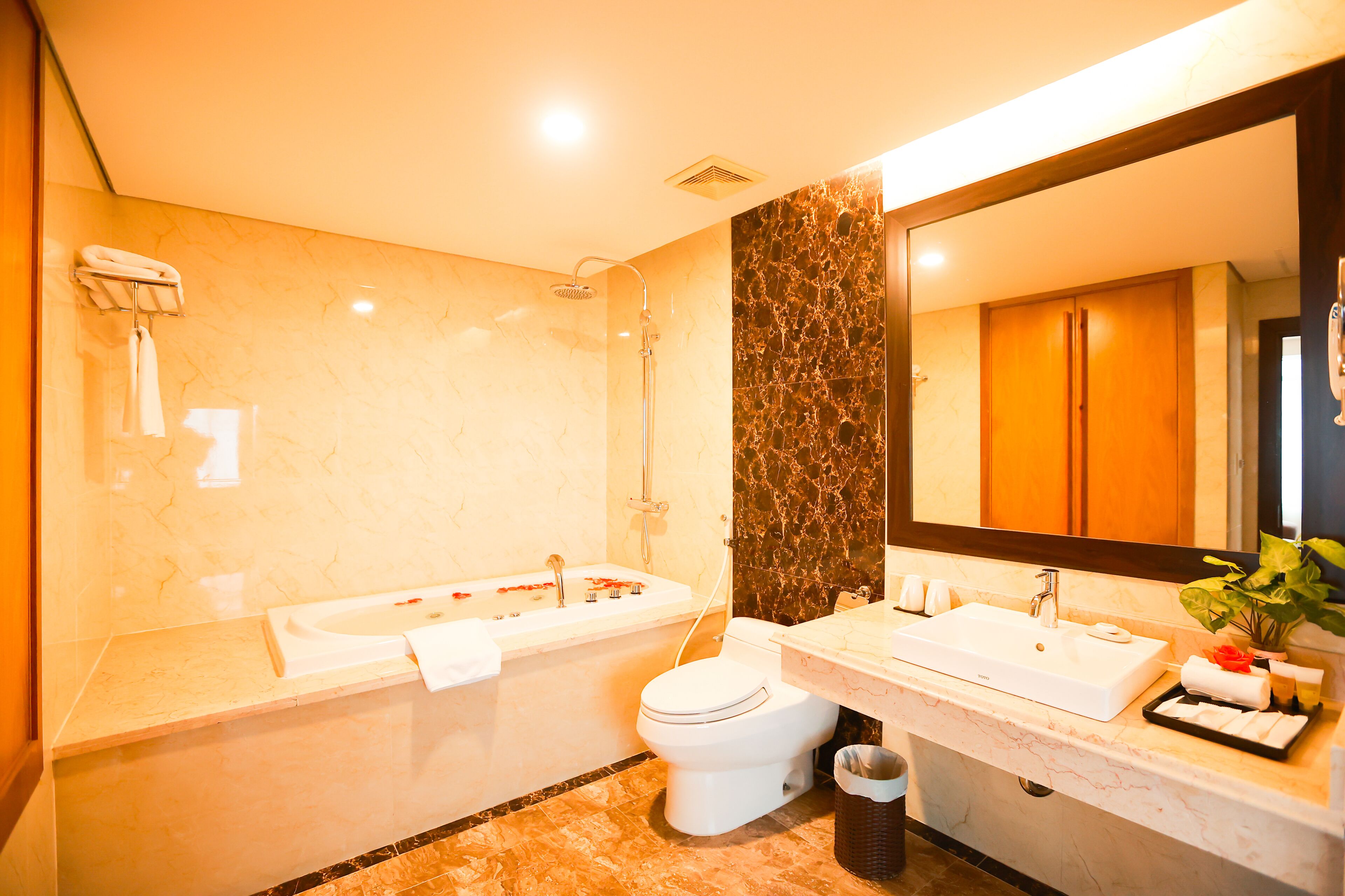 Un baño moderno con bañera, inodoro, lavamanos y un espejo grande.