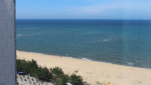 A beach view with a building in the foreground. - Muong Thanh Luxury Nhat Le Hotel (Dong Hoi)