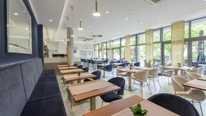 A modern dining area with long tables, chairs, and a seating area with benches. - Hotel Jastarnia (Jastarnia)