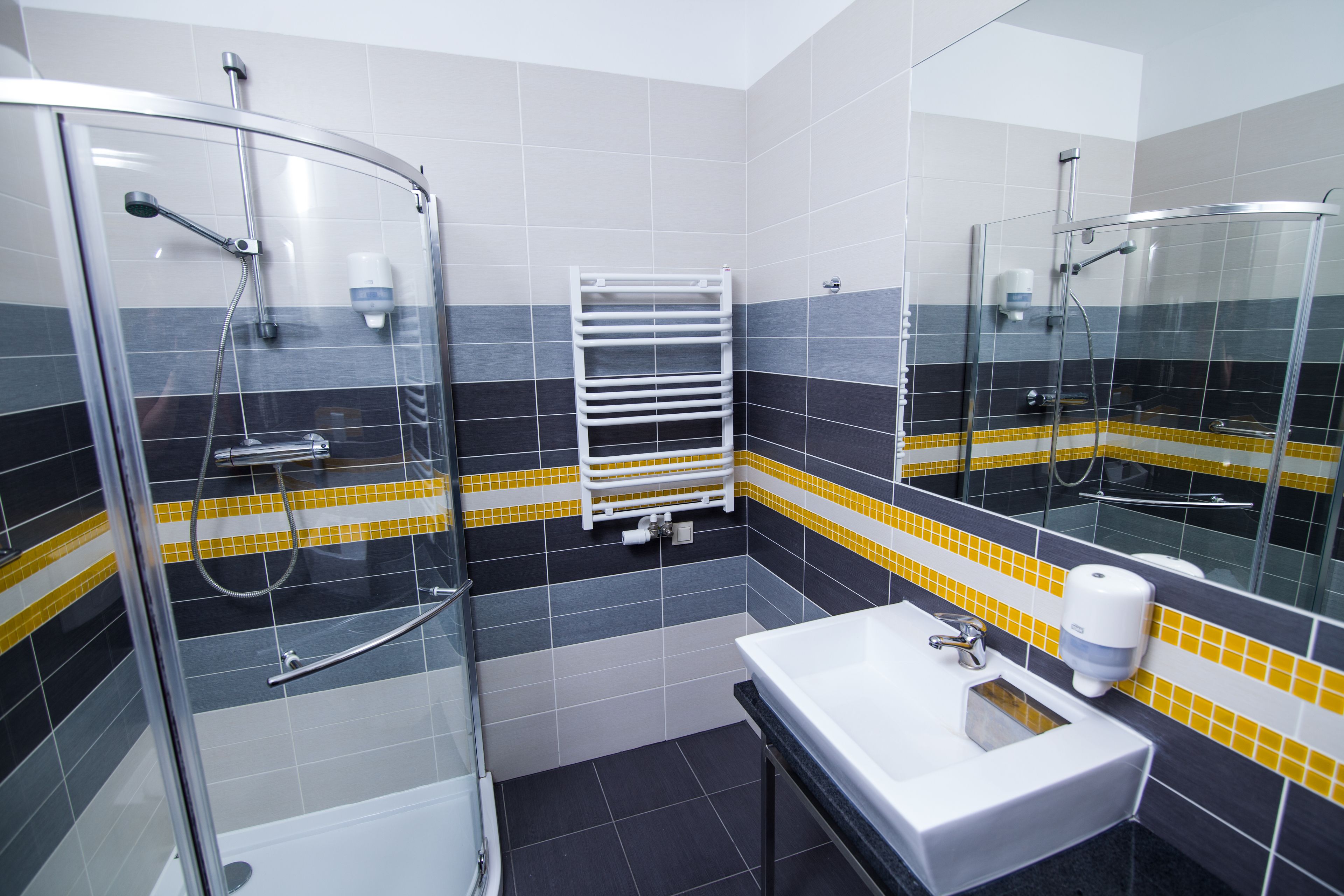 A modern bathroom with a glass-enclosed shower, a white sink, and a towel rack.