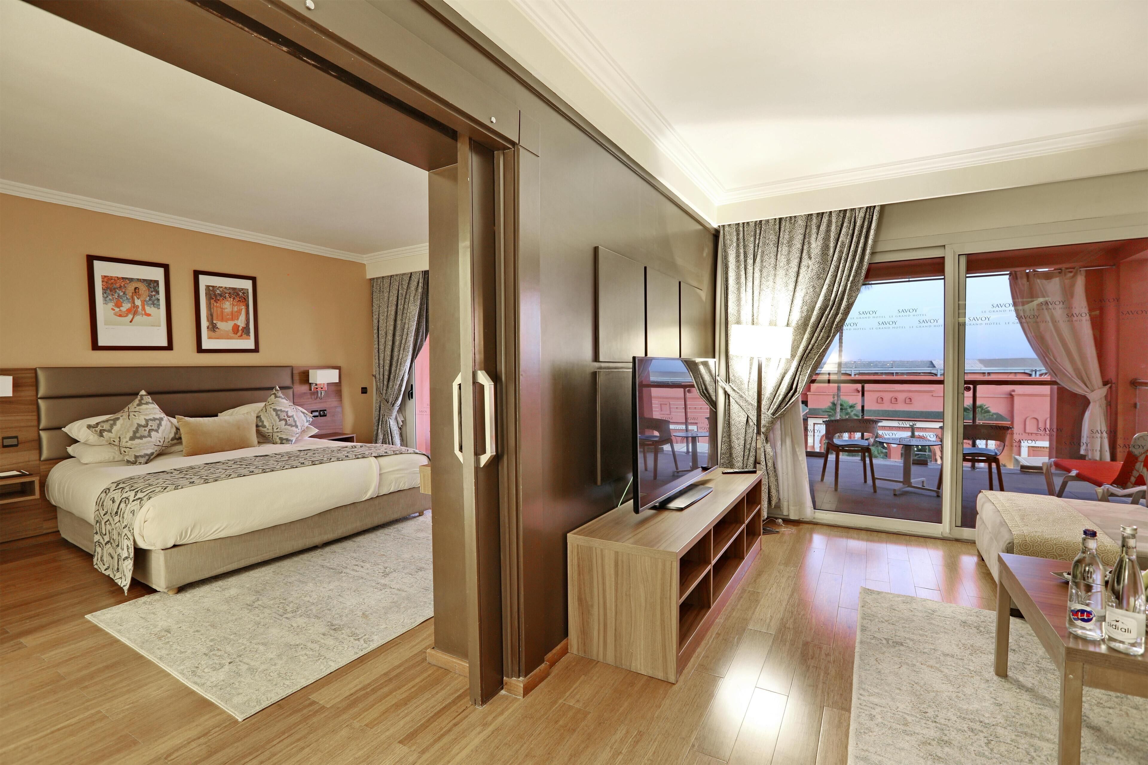 Una habitación de hotel con cama, televisión y balcón con vistas.