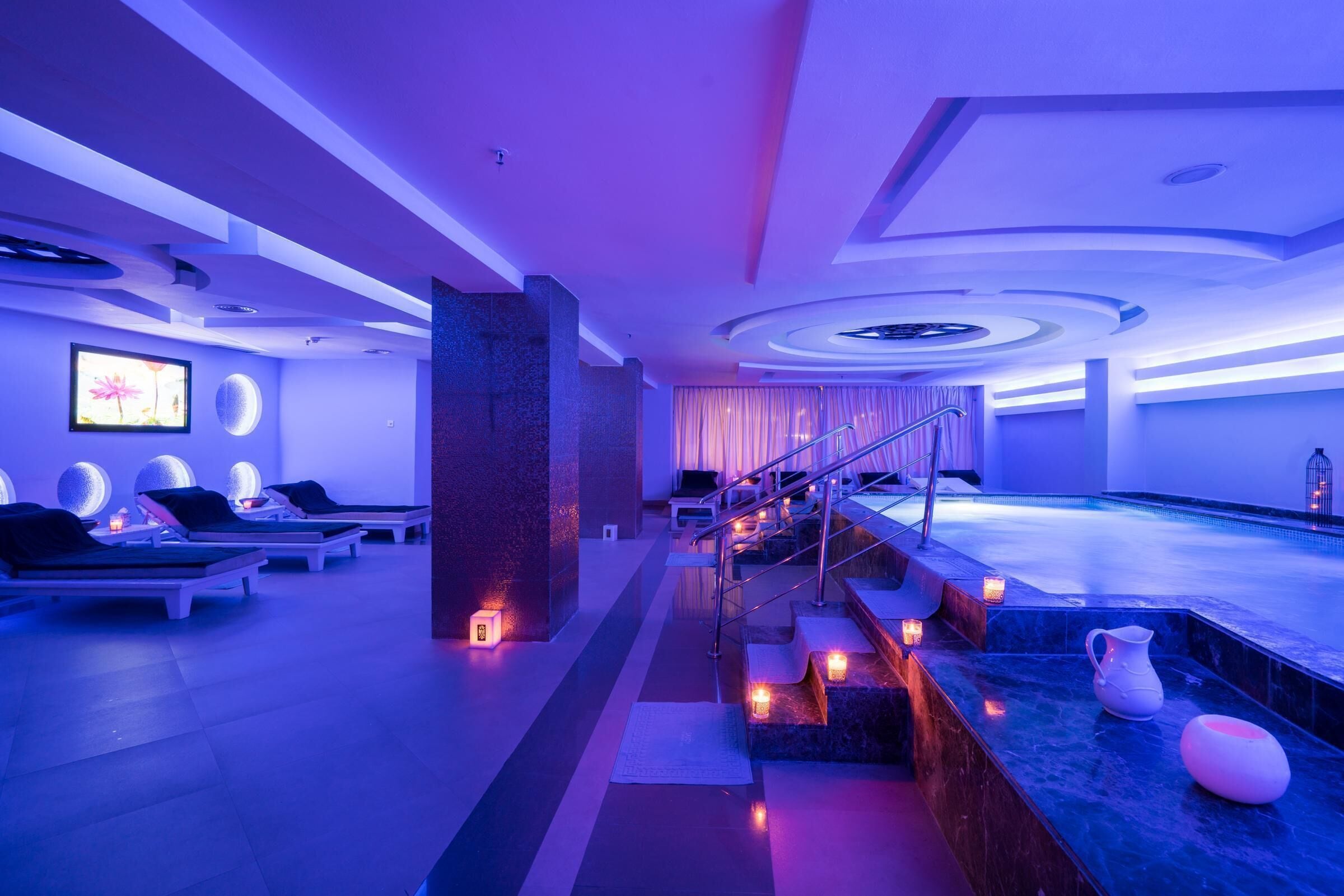 Un spa moderno con piscina, sillas de descanso y una escalera que lleva al área de la piscina.