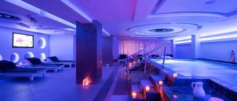 A modern spa with a pool, lounge chairs, and a staircase leading to the pool area.