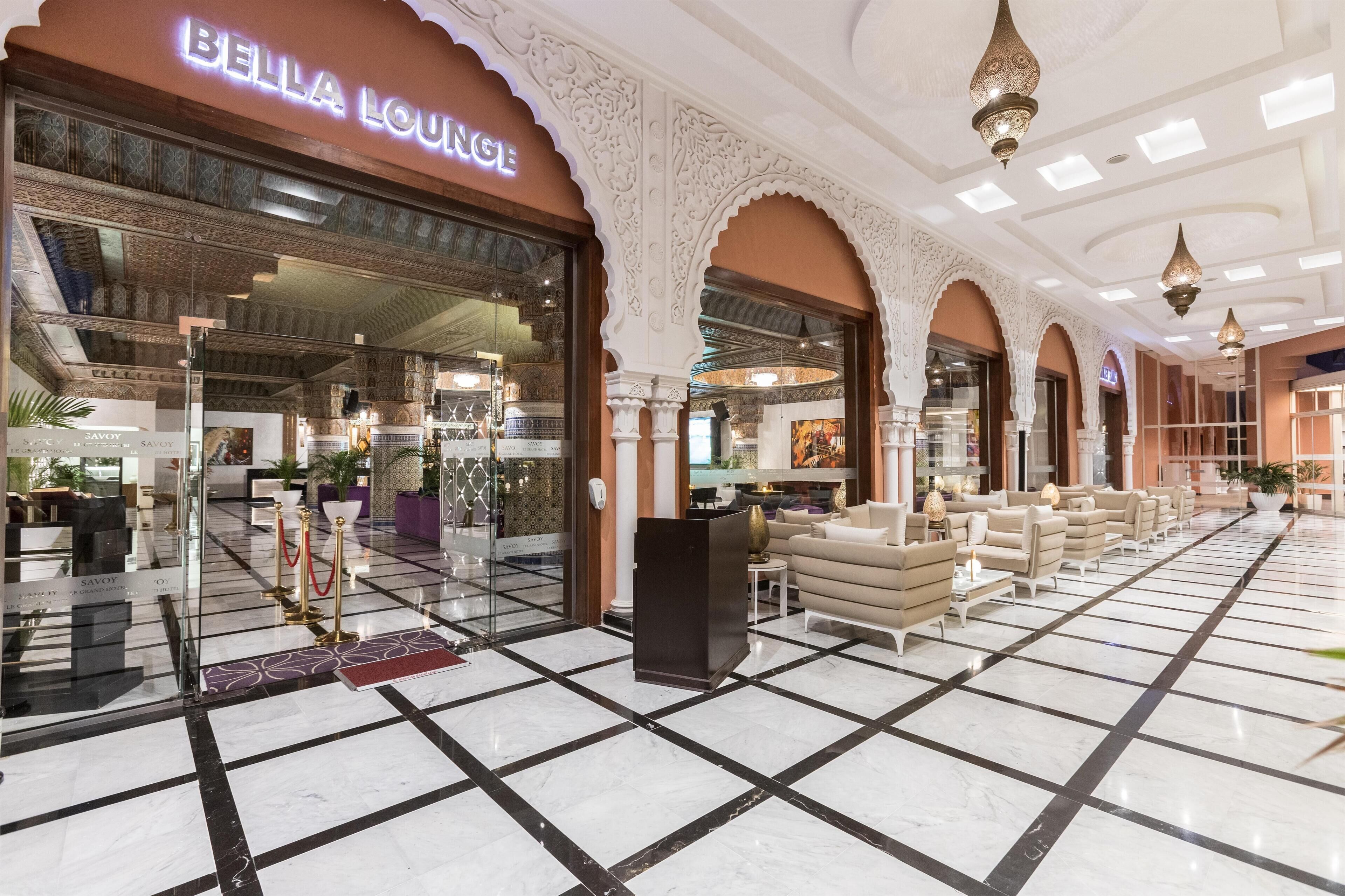 A lobby with a reception desk, seating area, and a Bella Lounge entrance.