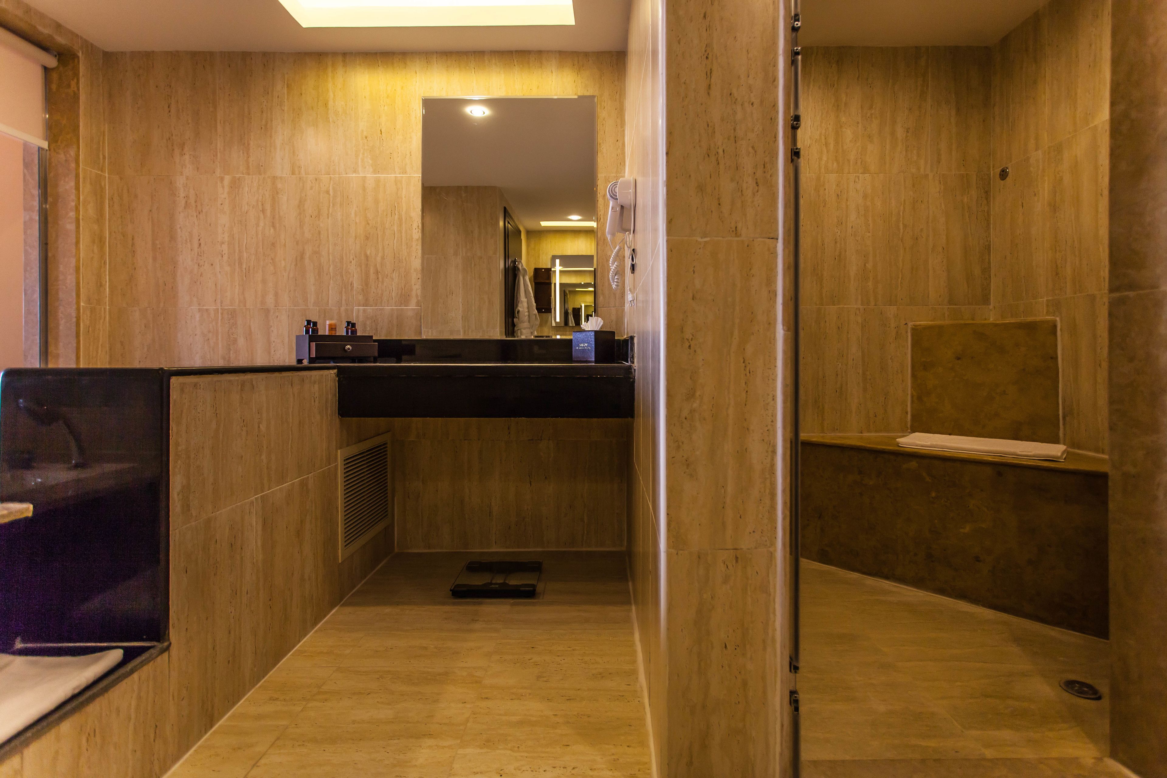 A modern bathroom with a wooden floor, a black countertop, and a mirror.