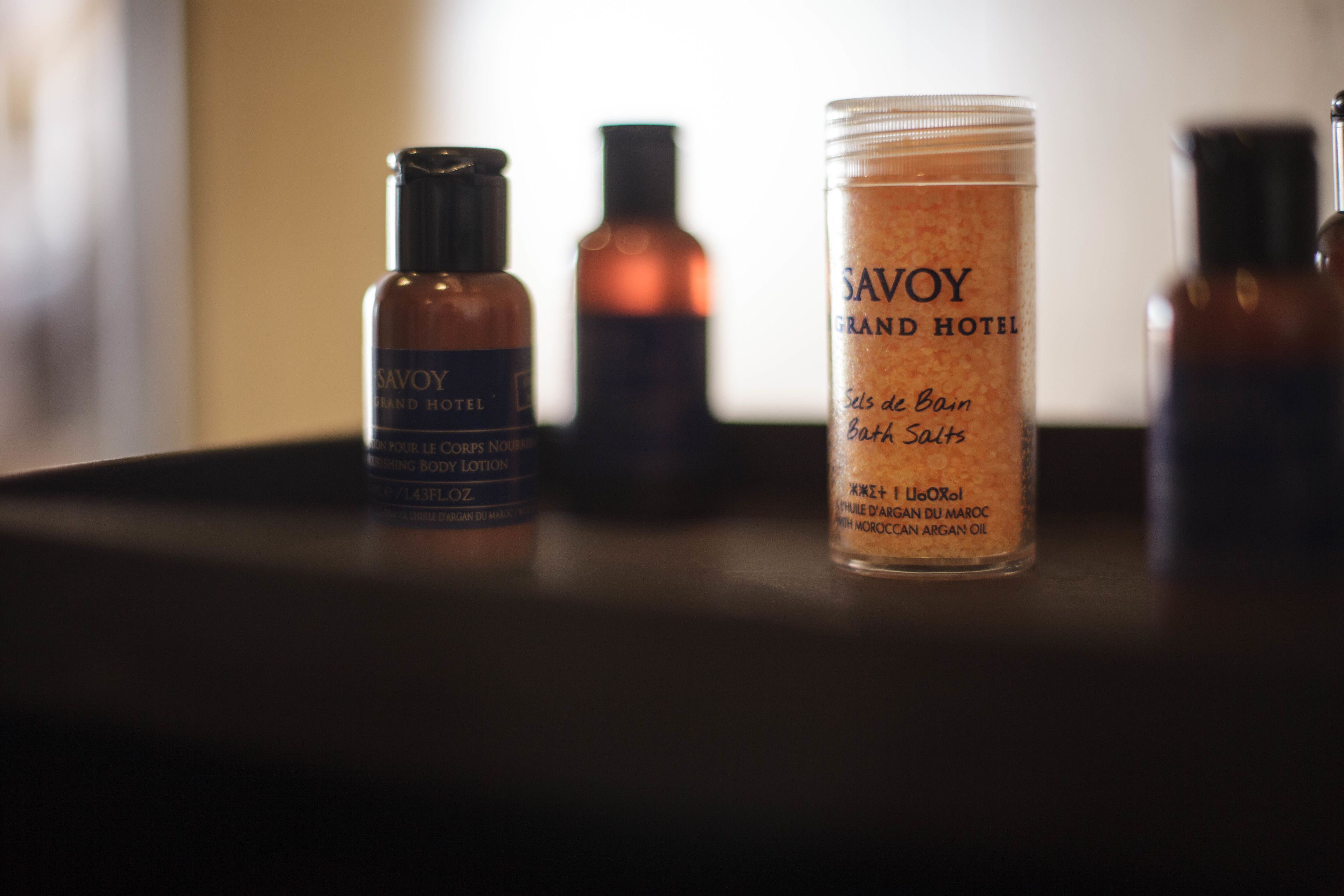A selection of Savoy Grand Hotel bath salts and body lotion on a table.