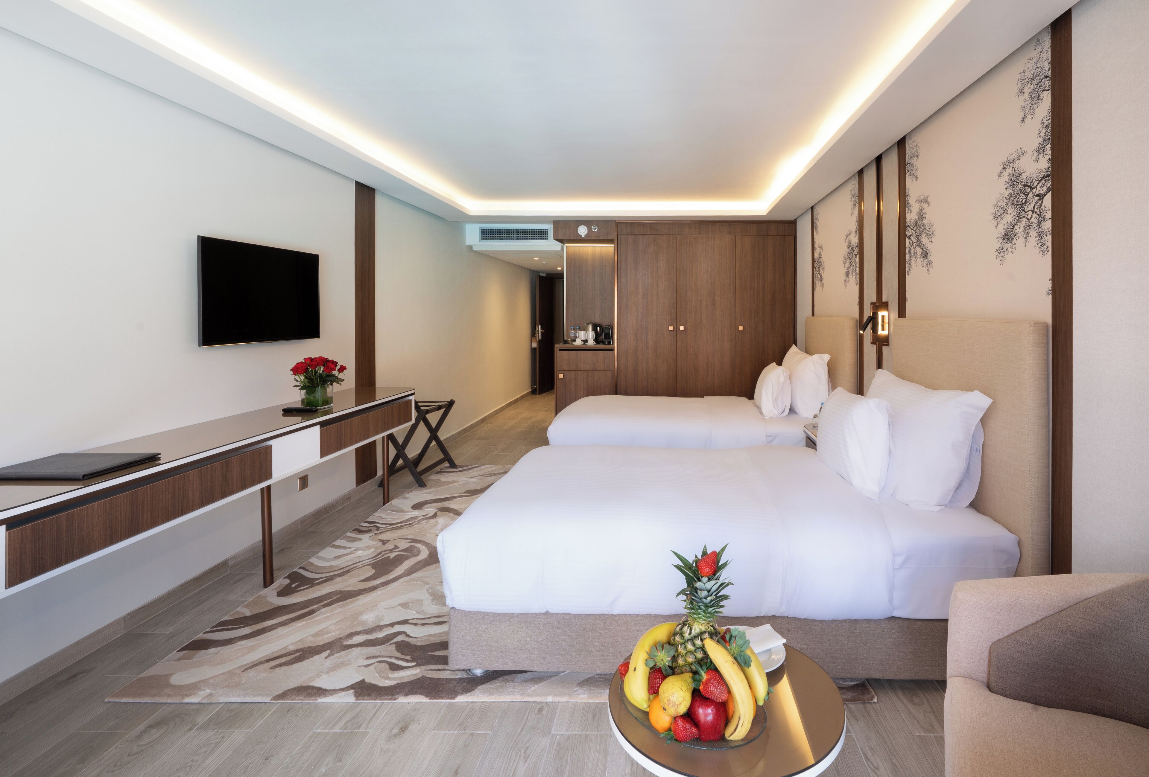 Een hotelkamer met een bed, nachtkastje, televisie en een fruitschaal op de vloer.