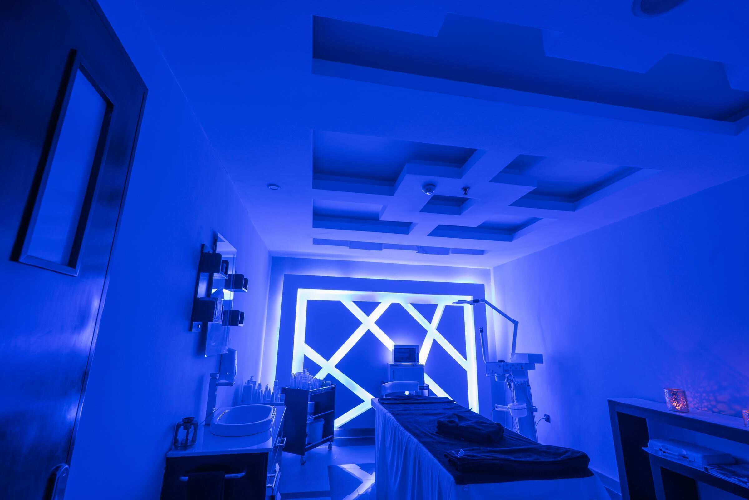 A room with a modern ceiling design, a bed, a desk, and a computer.