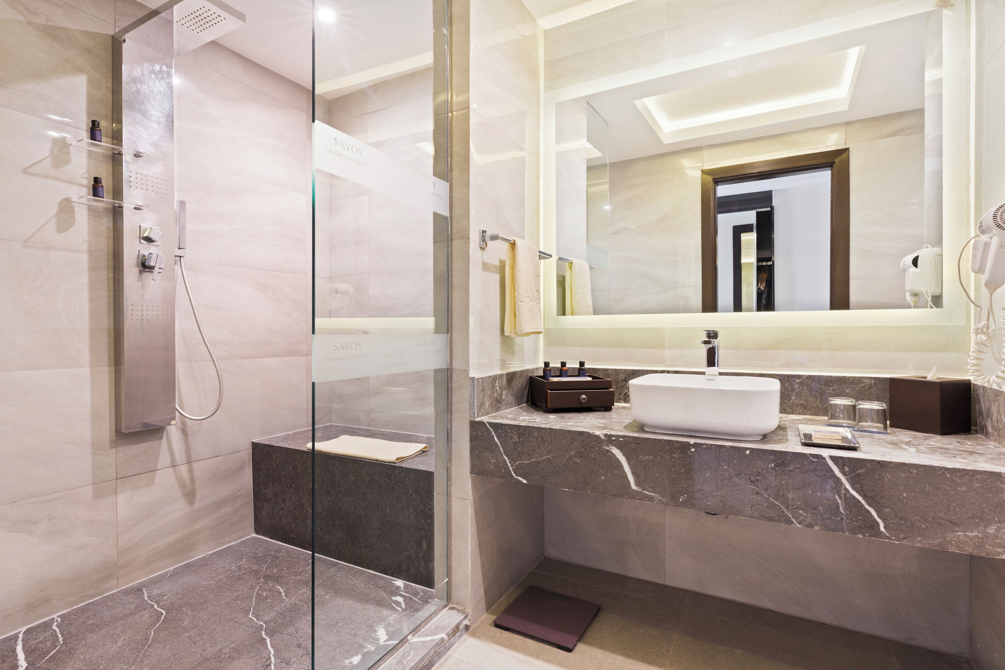 Un bagno moderno con cabina doccia in vetro, un lavabo in marmo e uno specchio grande.