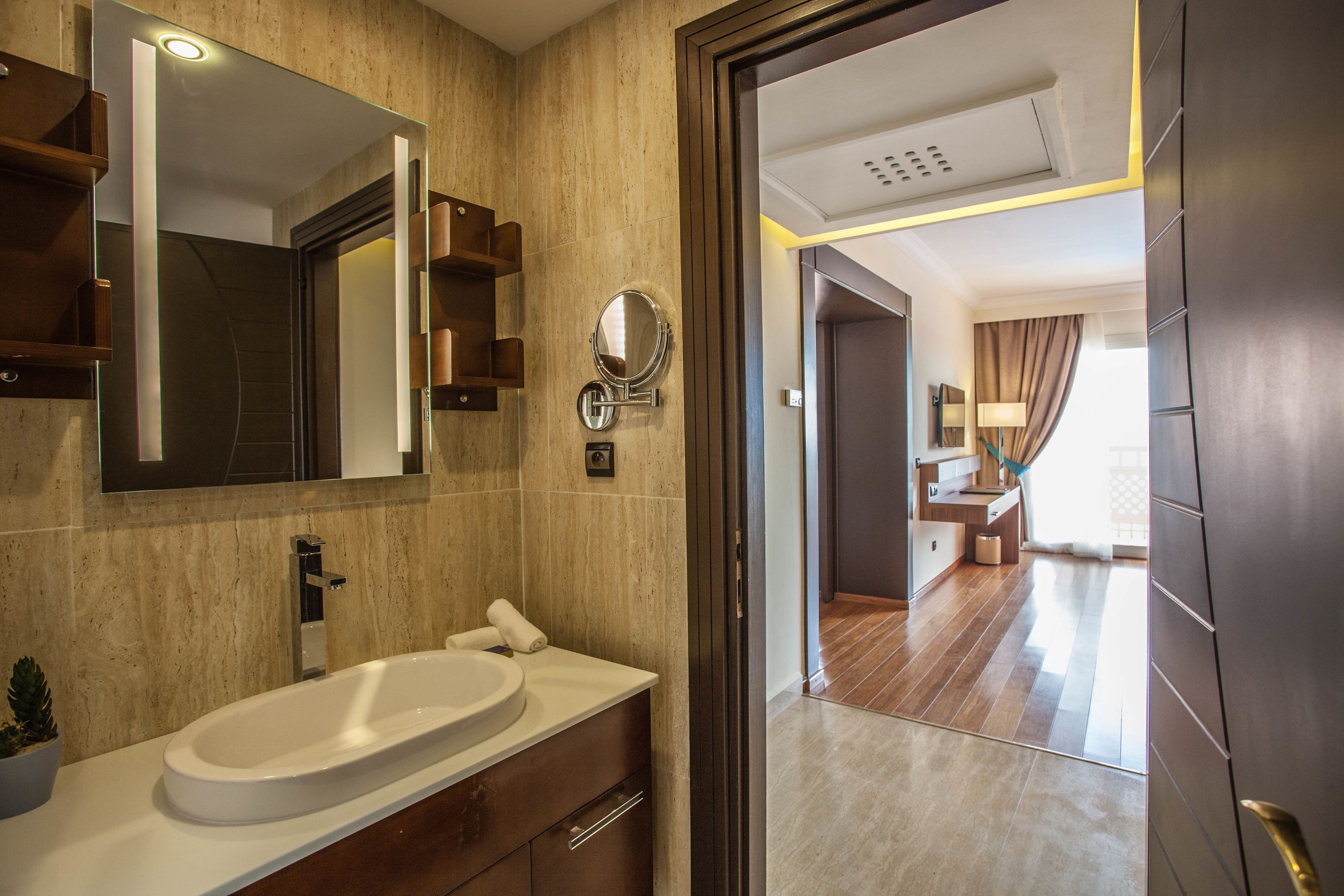 Une salle de bain moderne avec un grand miroir, un lavabo blanc et un meuble-lavabo en bois.