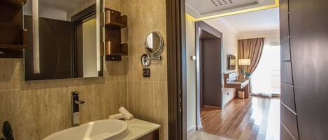 A modern bathroom with a large mirror, a white sink, and a wooden vanity.