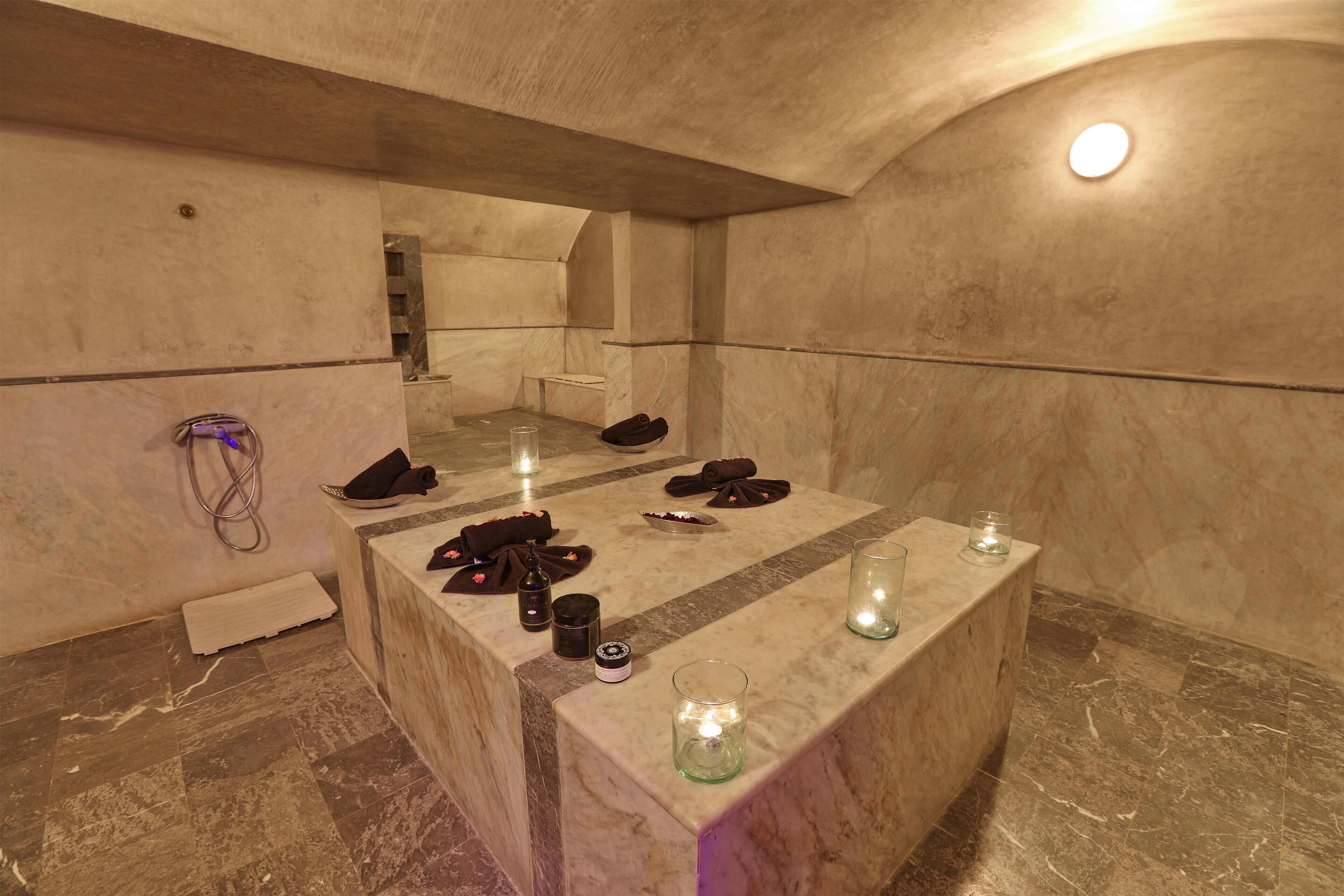 A marble-floored bathroom with a vanity, candles, and toiletries.